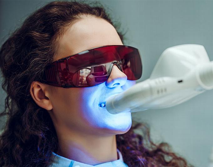 lady with teeth whitening light on teeth