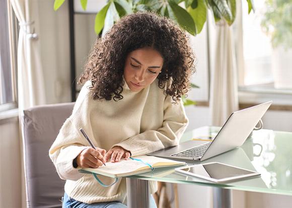 Lady studying on laptop taking notes